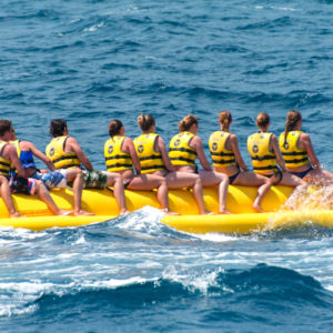 Banana boat in sea. Group of people riding banana boat