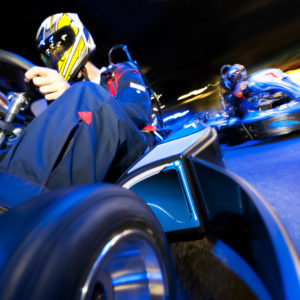 Two go-cart drivers batteling in a competitive race on an indoor circuit