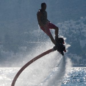 Flyboarder in silhouette spiralling over backlit waves