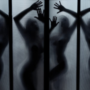 Silhouette of the naked lady dancing behind the glass