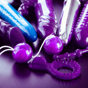 a collection of different types of sextoys, including dildo, vibrators and butt plugs over a dark wooden surface