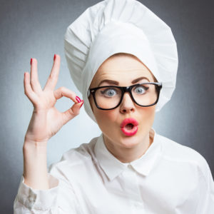 Young woman cook chef showing ok, isolated over gray wall