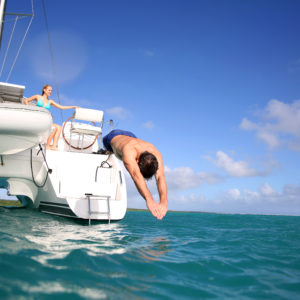 Man diving from catamaran deck into the sea