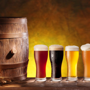Assortment of beer glasses with a wooden barrel. Background - dark yellow gradient.