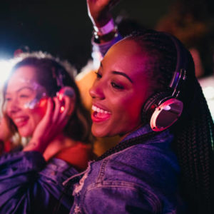 Young women are having fun and dancing in a silent disco at a music festival.
