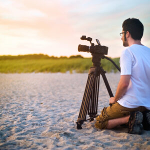 A videographer documenting a sunset on the beach.