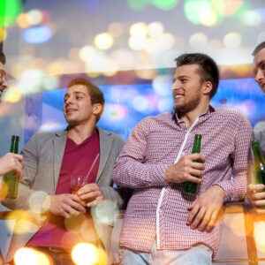 nightlife, party, friendship, leisure and people concept - group of smiling male friends with beer bottles drinking in nightclub